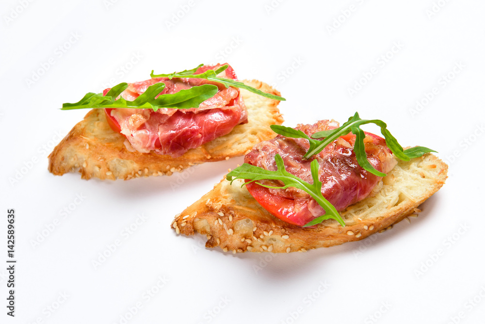 Two sandwiches with serrano ham, cheese and arugula Two sandwiches with serrano ham, cheese and arugula