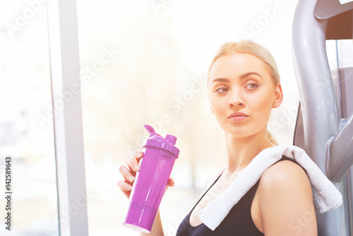 Young athletic woman drinking water in a gym.