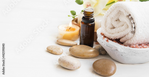 Spa setting with essence bottle, cotton towel,massage stones and candle