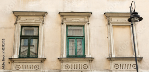Vintage design green windows on the facade of the old house with street lamp in the foreground