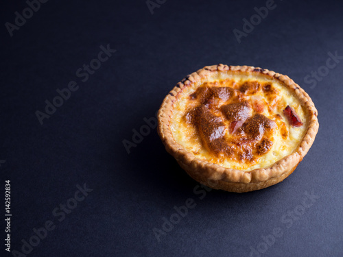 Small quiche lorraine pie isolated on black background