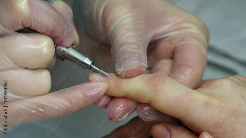 Cleaning of cuticles on female fingers. Girl in a nail salon receiving a manicure Cleaning of cuticles on female fingers. Girl in a nail salon receiving a manicure
