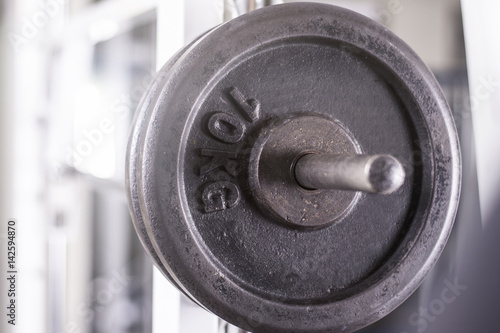 Close up of a weightlifting machine. Focus on weights. Lens flare in background.