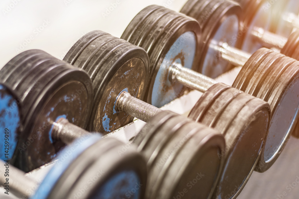 Old school gym interior with equipment bodybuilding background. Heavy iron dumbbells stacked in rows. Stock Adobe Stock