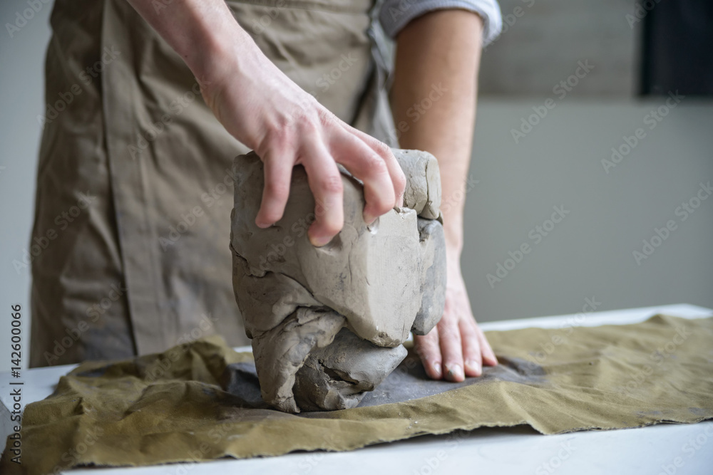 Man crumples piece of white clay for sculpting