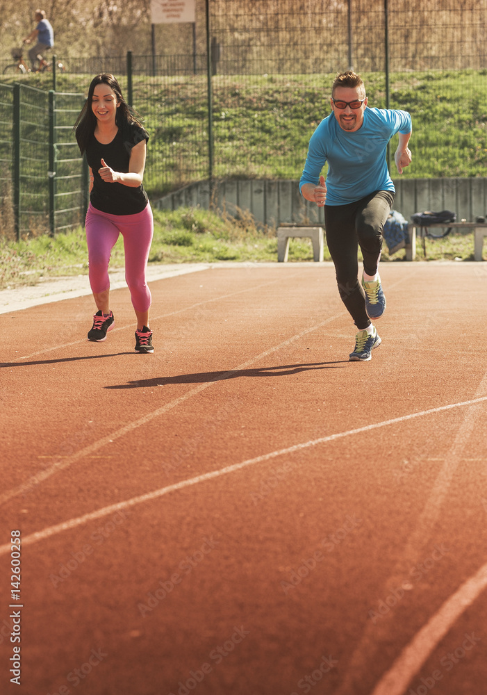 Fototapeta premium Young couple exercise on athletics track