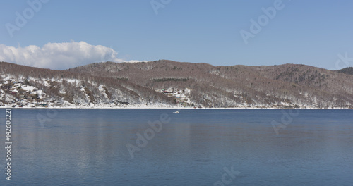Baikal lake spring landscape view. Snow-covered shore of the lake. Rocky forested coastline. © anya babii