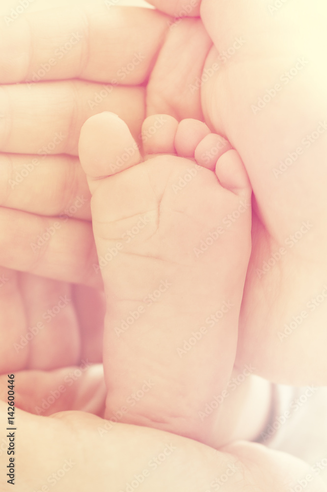 Closeup of mother hands holding cute tiny baby feet, showing baby foot. Selective focus. Toned. Closeup of mother hands holding cute tiny baby feet, showing baby foot. Selective focus. Toned.