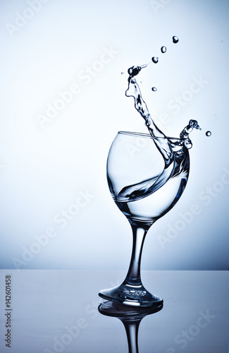 Water splashing out of a tall wine glass.