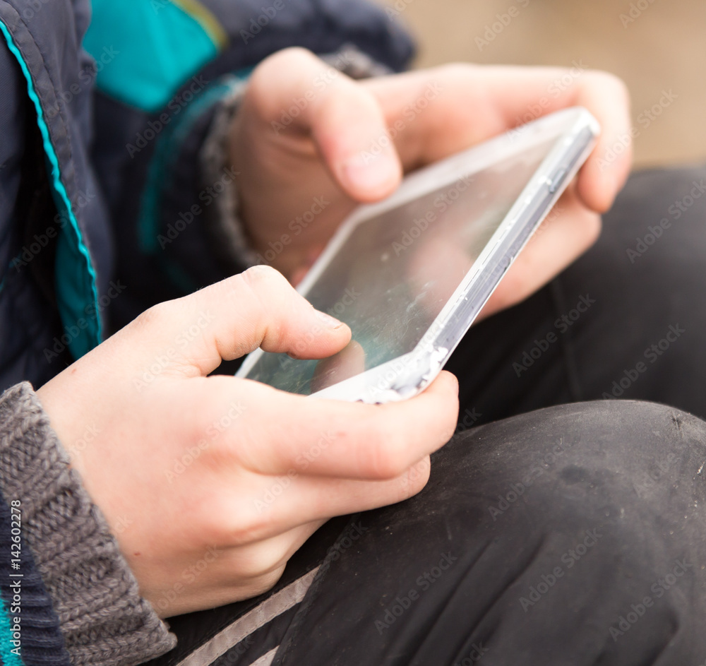 Obraz premium Boy playing computer games on a cell phone
