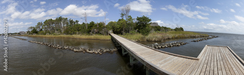 Panel kuchenny z motywem Wooden walkway across body of water leading to island under blue sky.