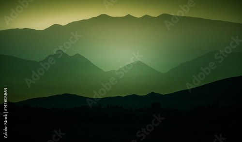 A beautiful, colorful, abstract mountain landscape with a hot summer haze in warm green tonality. Decorative, artistic double exposure.
