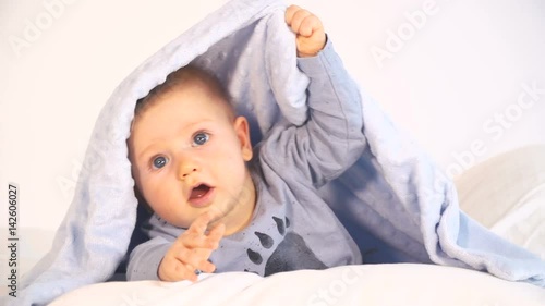 baby mit großen blauen augen und blonden haaren im bett