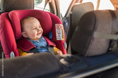 Father fasten his baby in car seat photo