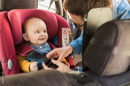 Foto Father fasten his baby in car seat