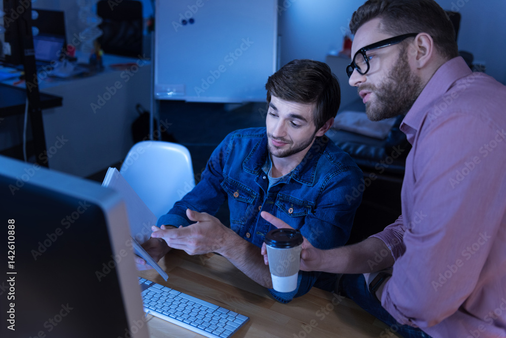 Nice handsome man showing his notes to a colleague Nice handsome man showing his notes to a colleague