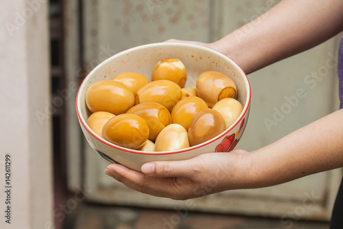 hand holding boiled egg mix with Black Soy Sauce in bowl