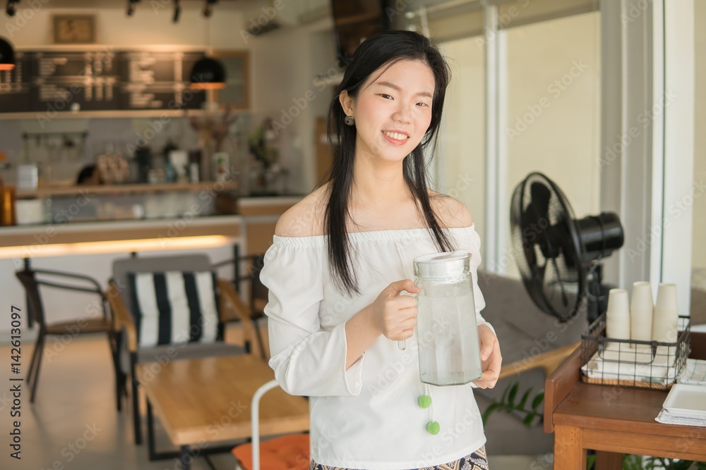Young Chinese woman Waitress serving water in coffee shop - Glass pitcher of water. Young Chinese woman Waitress serving water in coffee shop - Glass pitcher of water.