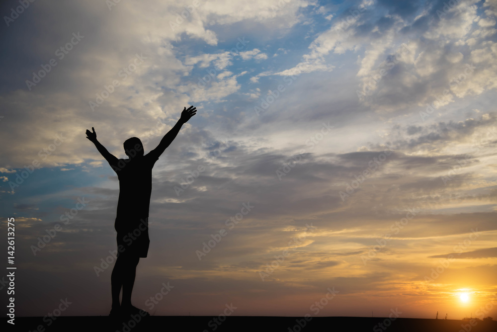 Silhouette of a man with hands raised in the sunset. Silhouette of a man with hands raised in the sunset.