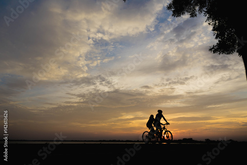 Silhouette of a woman and man biker in the sunset