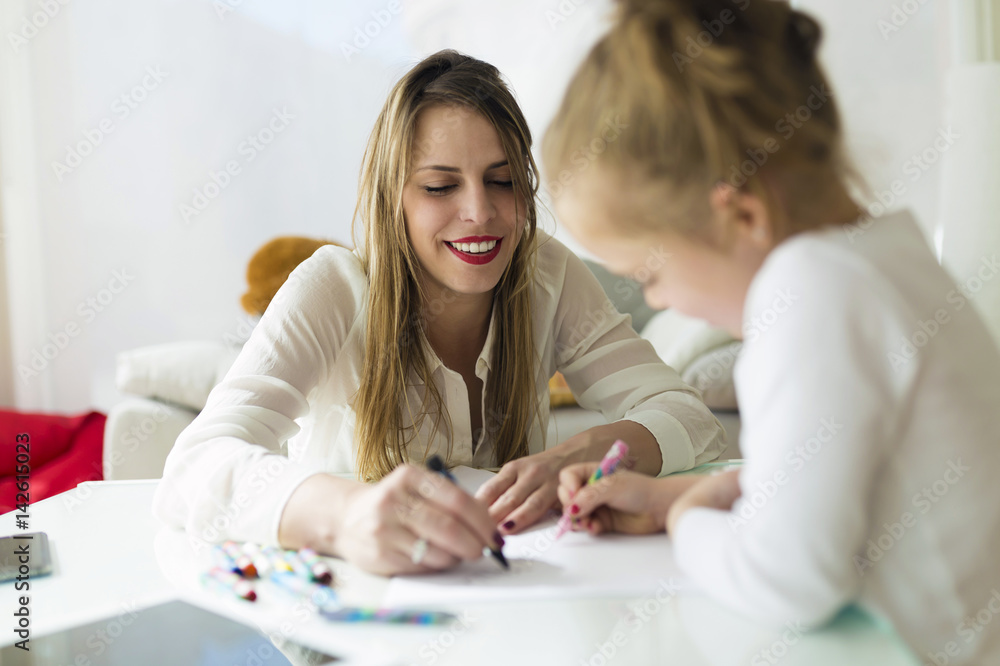 Beautiful mother with her daughter drawing with crayons at home. Beautiful mother with her daughter drawing with crayons at home.