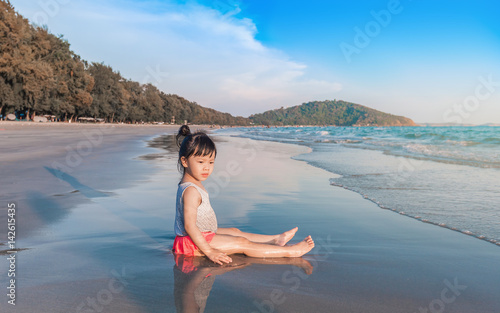 little girl 2-3 years plays on the beach in sunset