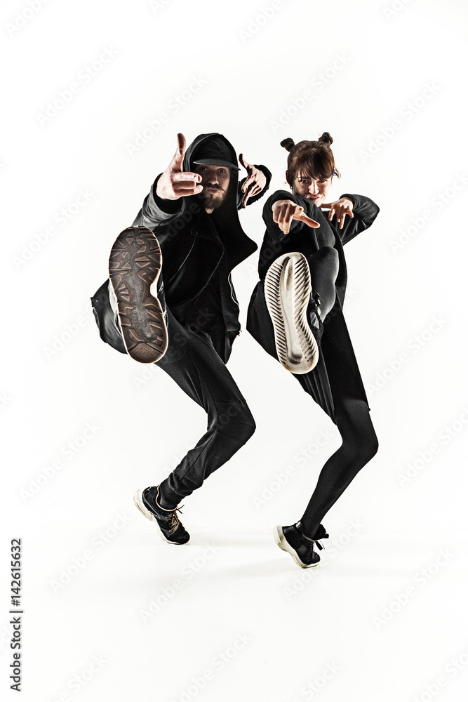 The silhouettes of two hip hop male and female break dancers dancing on white background