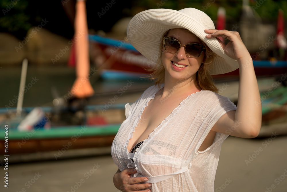 Young blonde woman in bikini and beach dress wearing white hut