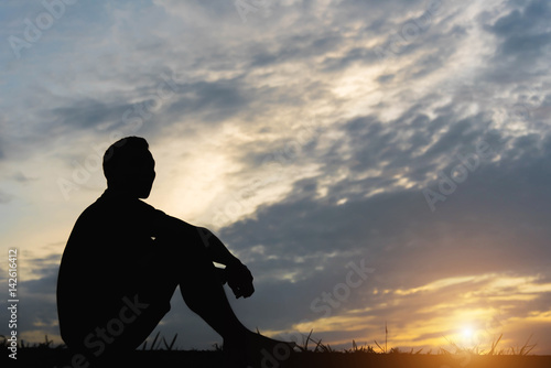 Silhouette of a man sitdown with so sad in the sunset.