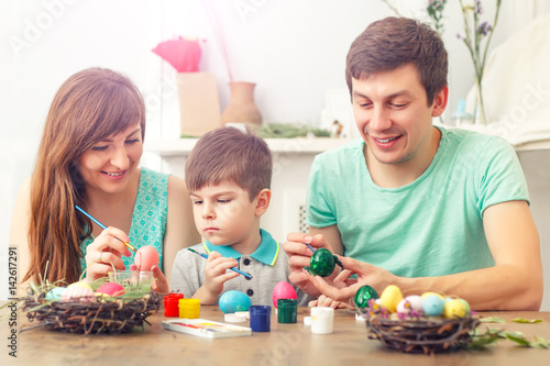 Mother, father and son are painting eggs. Happy family are preparing for Easter.