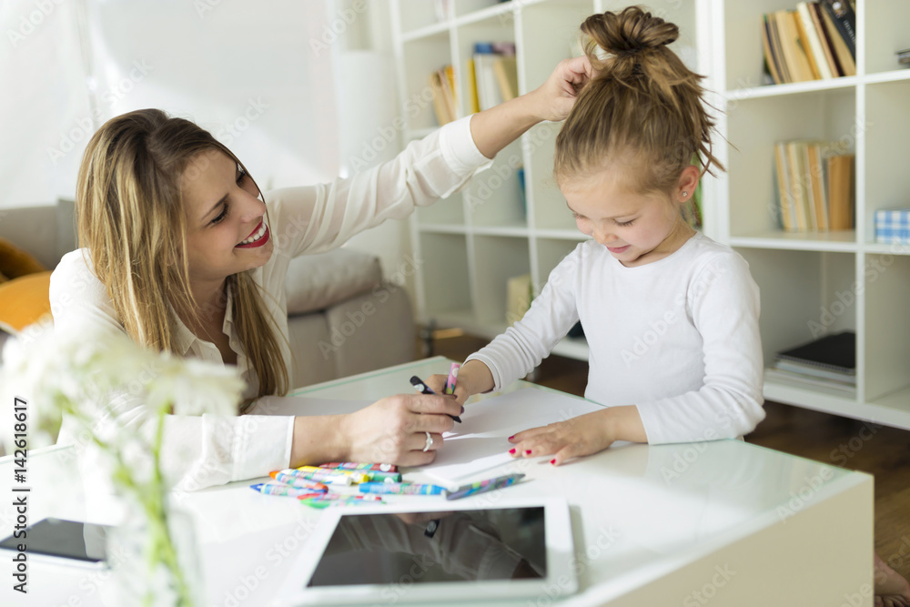 Beautiful mother with her daughter drawing with crayons at home. Beautiful mother with her daughter drawing with crayons at home.