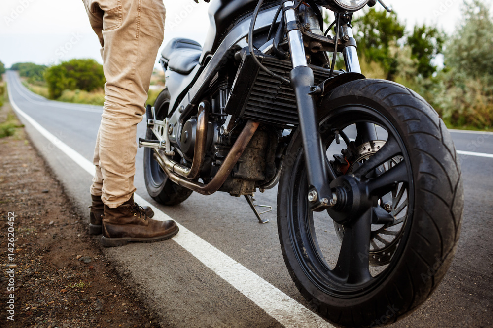 Young handsome man posing near his motorbike at countryside road. Young handsome man posing near his motorbike at countryside road.