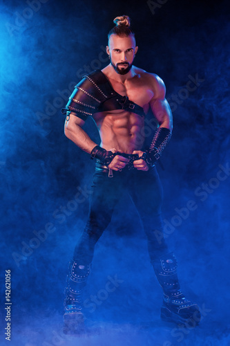 Handsome young sexy man with beautiful muscular chest in interesting costume on the scene