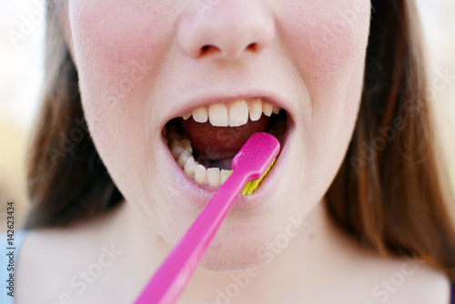 Portrait of a beautiful young woman holding toothbrush in the park.