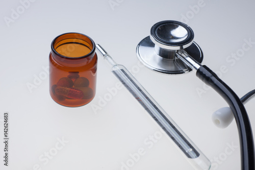 various medicine drugs with thermometer and stethoscope on lab light table