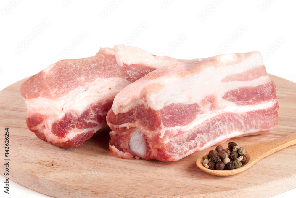 pieces of pork with peppercorn on a cutting board isolated on white background
