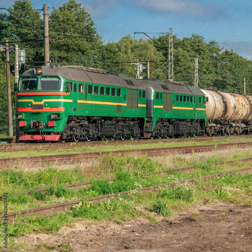 Freight train with tank wagons moving in forest. Green diesel ca Freight train with tank wagons moving in forest. Green diesel ca