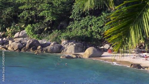 Peaceful hidden beach with swimmers in shallow topical waters causally drifting in the exotic Asian waters of the Andaman sea in Phuket Thailand. photo