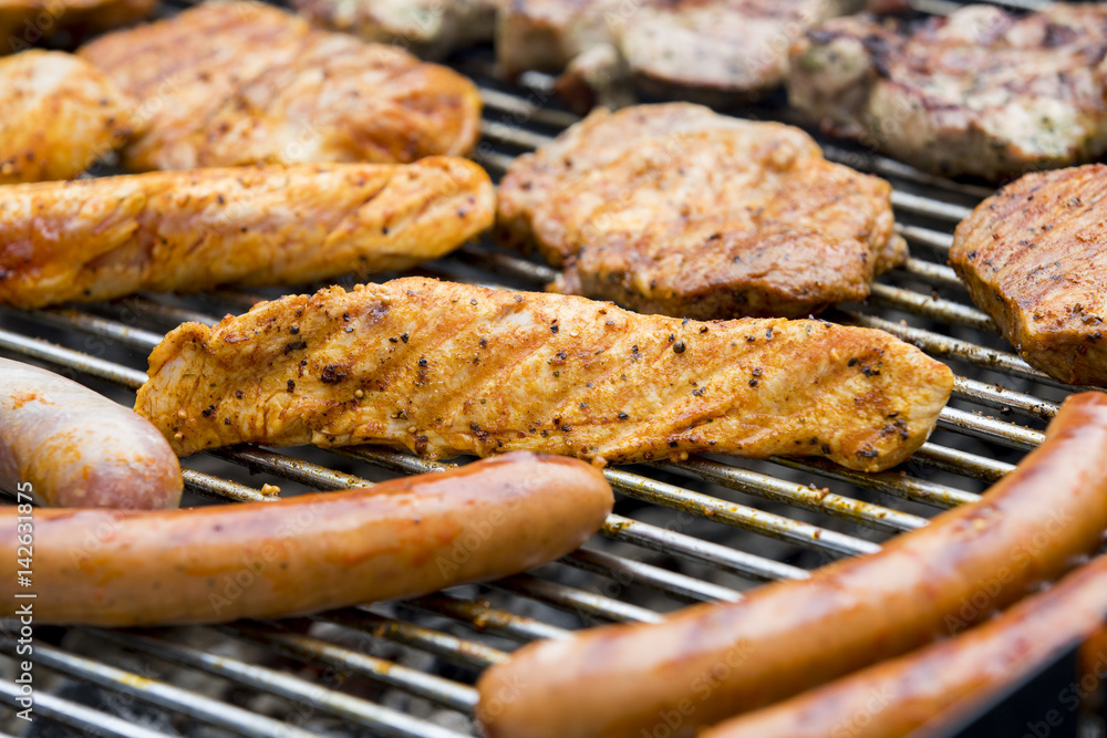 Fleisch und Wurst werden auf einem Grill zubereitet