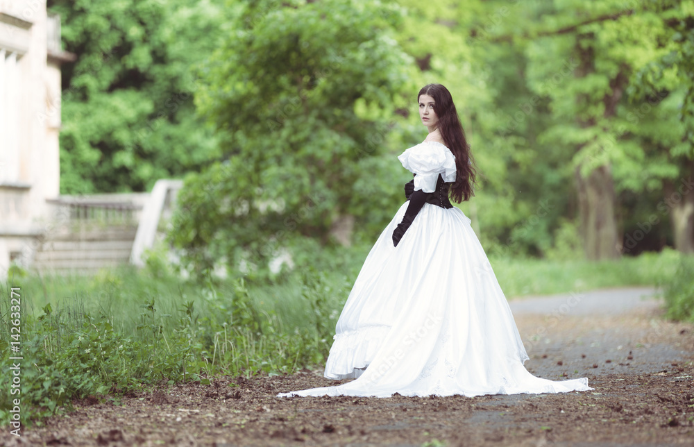 Woman in white Victorian dress in spring park