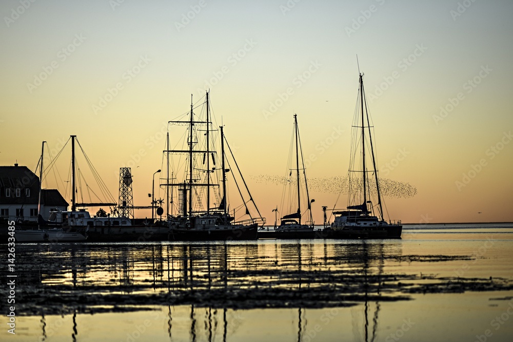 Sunset over a anchored sailboats in marine.
