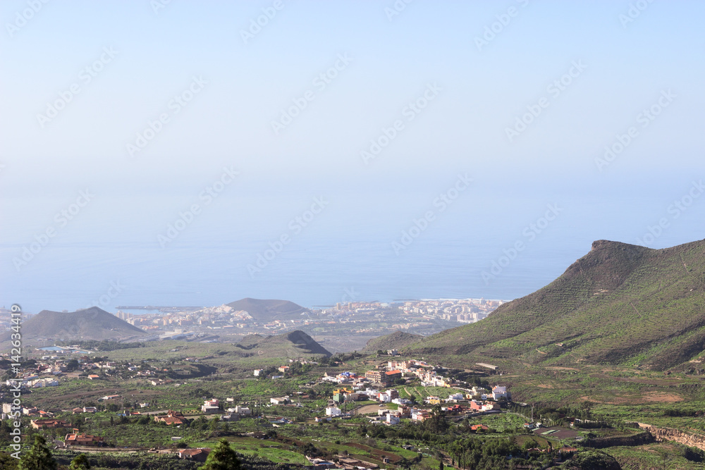 Southern part of Tenerife island with small villages at the mountain slopes and Las Americas city on the Atlantic coast, aerial view from mirador. Canary islands, Spain