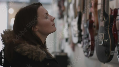 Young adult female looking at guitar in shop