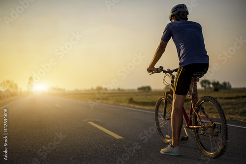 Rider is riding the bicycle on the road with sunset background. Exercise and health day.