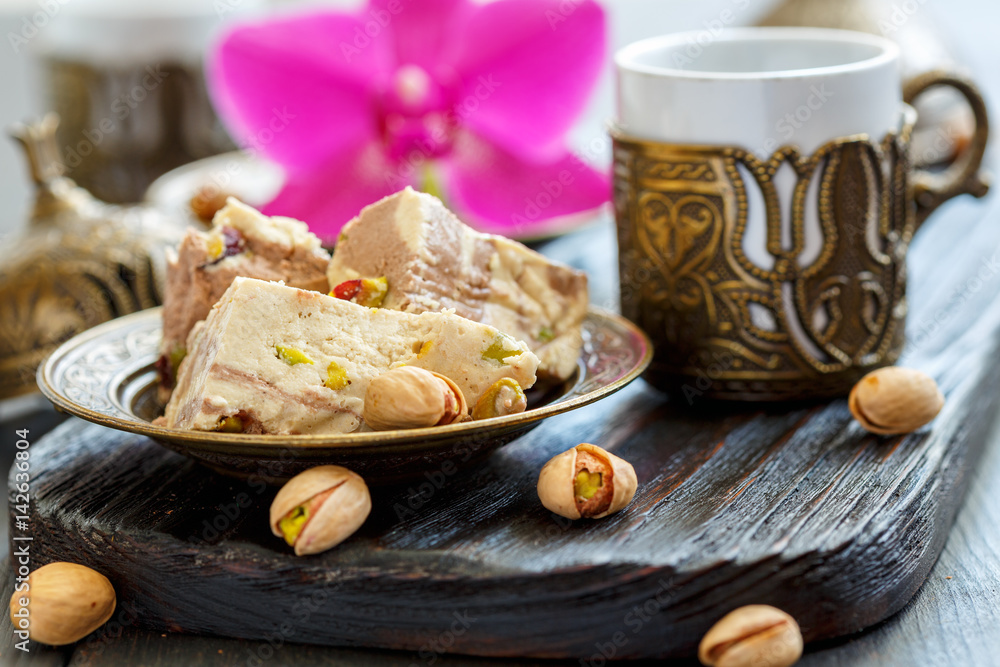 Tahini halva with pistachios on a bronze plate.