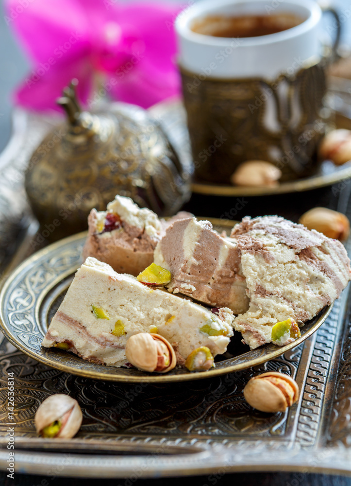 Tahini halva with cocoa and pistachio nuts closeup on a bronze plate. Tahini halva with cocoa and pistachio nuts closeup on a bronze plate.