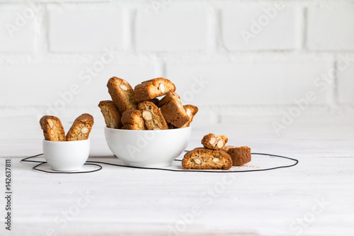 Biscotti or cantuccini, Italian almond biscuits (cookies) - twice-baked, oblong-shaped, dry, crunchy, and dipped in a drink (wine) photo