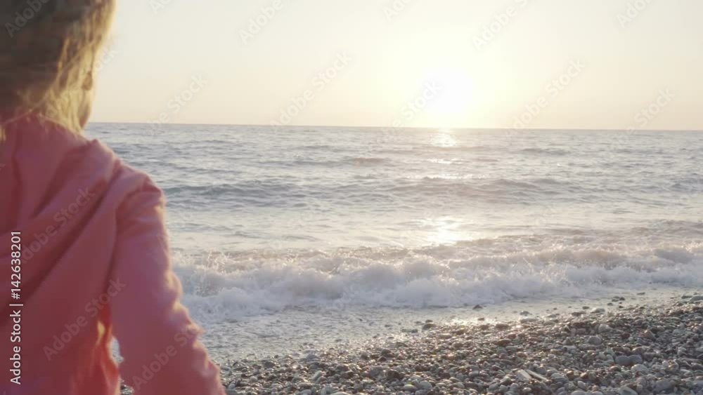 little girl runs to meet the sun on the beach and happily jumps little girl runs to meet the sun on the beach and happily jumps