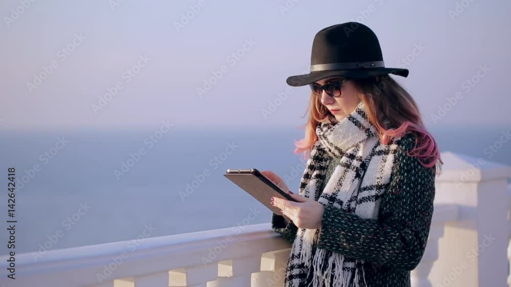 Beautiful brunette using digital tablet touch screen. Hipster girl with tablet computer on the beach Beautiful brunette using digital tablet touch screen. Hipster girl with tablet computer on the beach