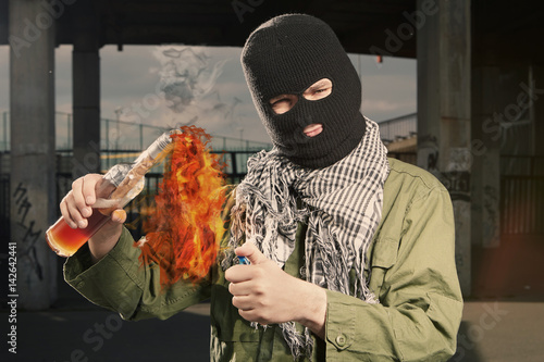 Anarchist in balaclava lighting molotov cocktail glass bomb